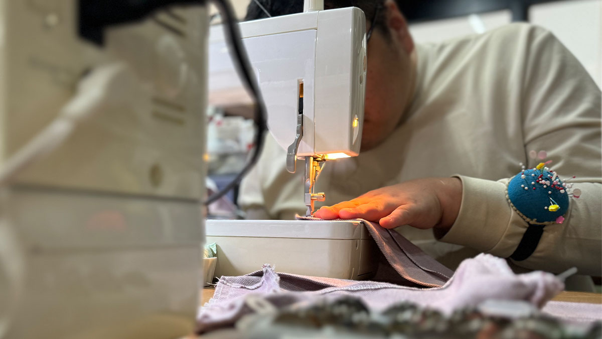 縫製の仕事の写真。服やバッグを布から作り出す作業。型紙に合わせて裁ち鋏で裁断した生地を、ミシンを使って縫い合わせている様子。